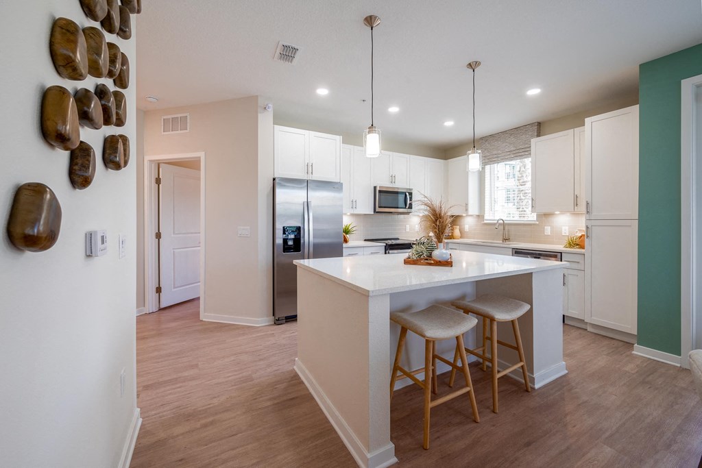 a kitchen with white cabinets and a white island with two stools