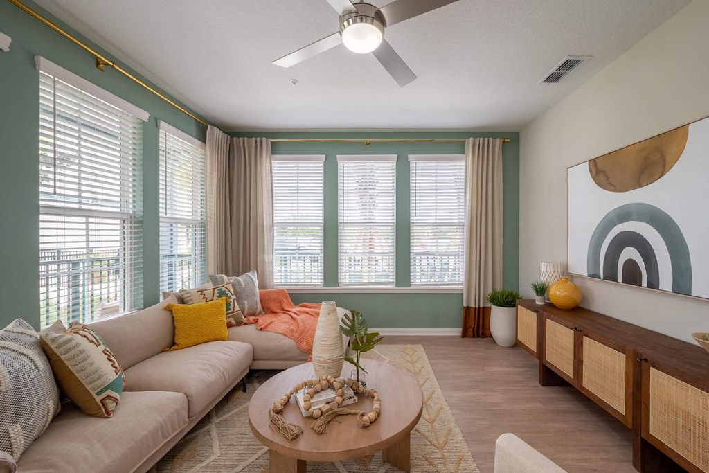 furnished living room with large windows and a ceiling fan