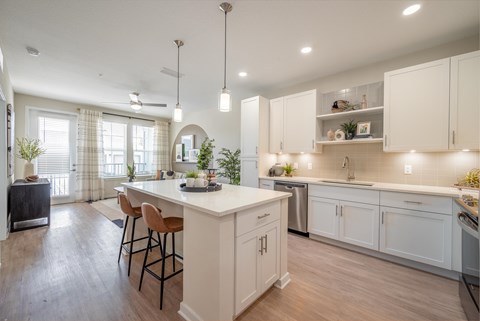 an open kitchen and dining area with white cabinets and a white counter top