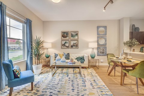 A living room with a blue chair, a white couch, and a rug with blue and yellow flowers.