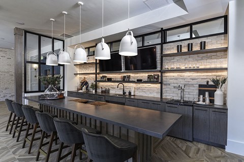 a kitchen with a long bar and chairs and a tv
