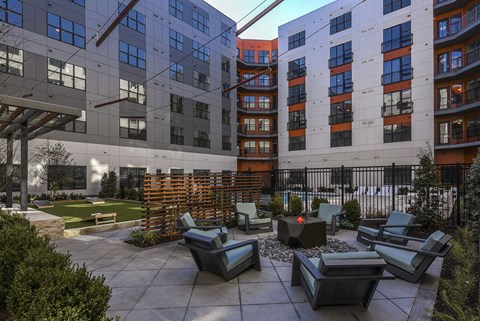 a courtyard with chairs and a fire pit in front of an apartment building