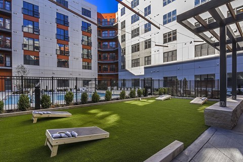 an outdoor lounge area with grass and a pool in front of buildings