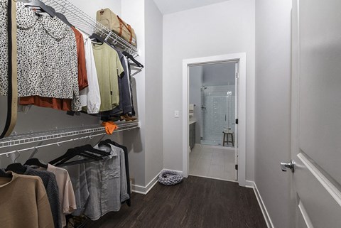 a closet with a rack of clothes and a door to a bathroom