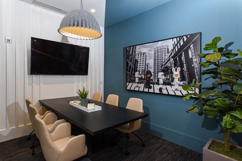 a conference room with a table and chairs and a tv on the wall