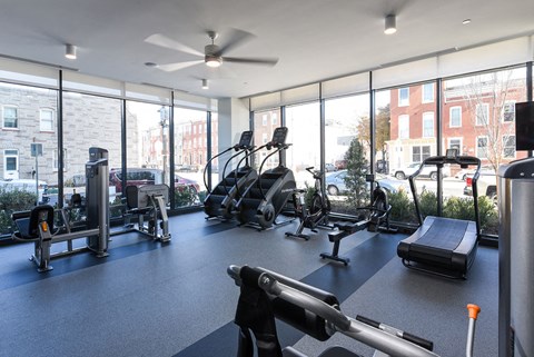 a gym with cardio equipment and windows in a building