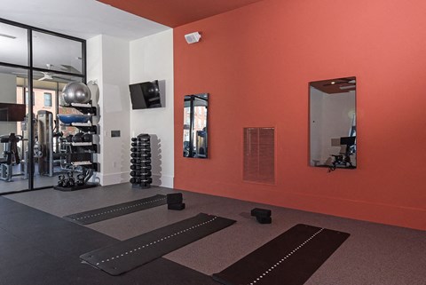 a gym with yoga mats on the floor and a red wall