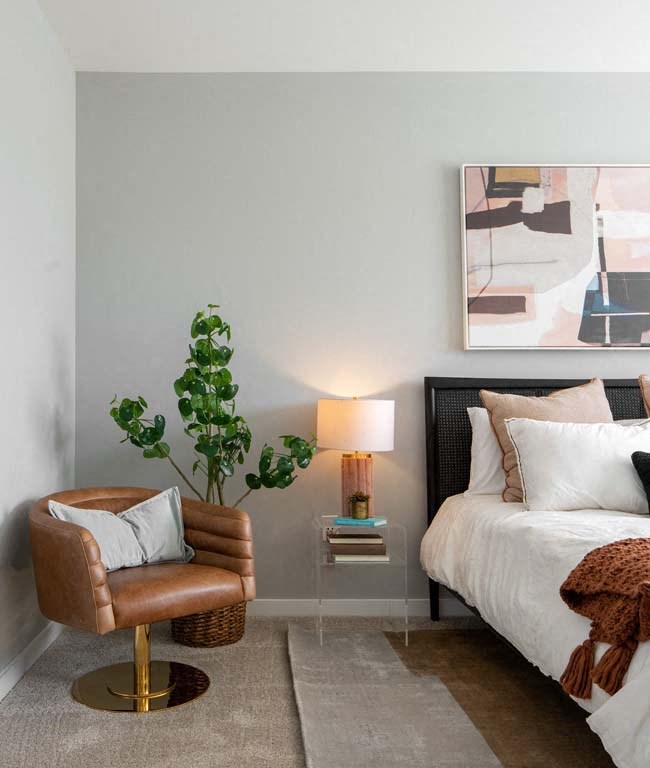 a bedroom with a bed and a chair and a plant