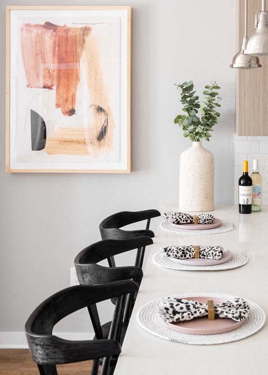 a dining table with two black chairs and a vase with a plant