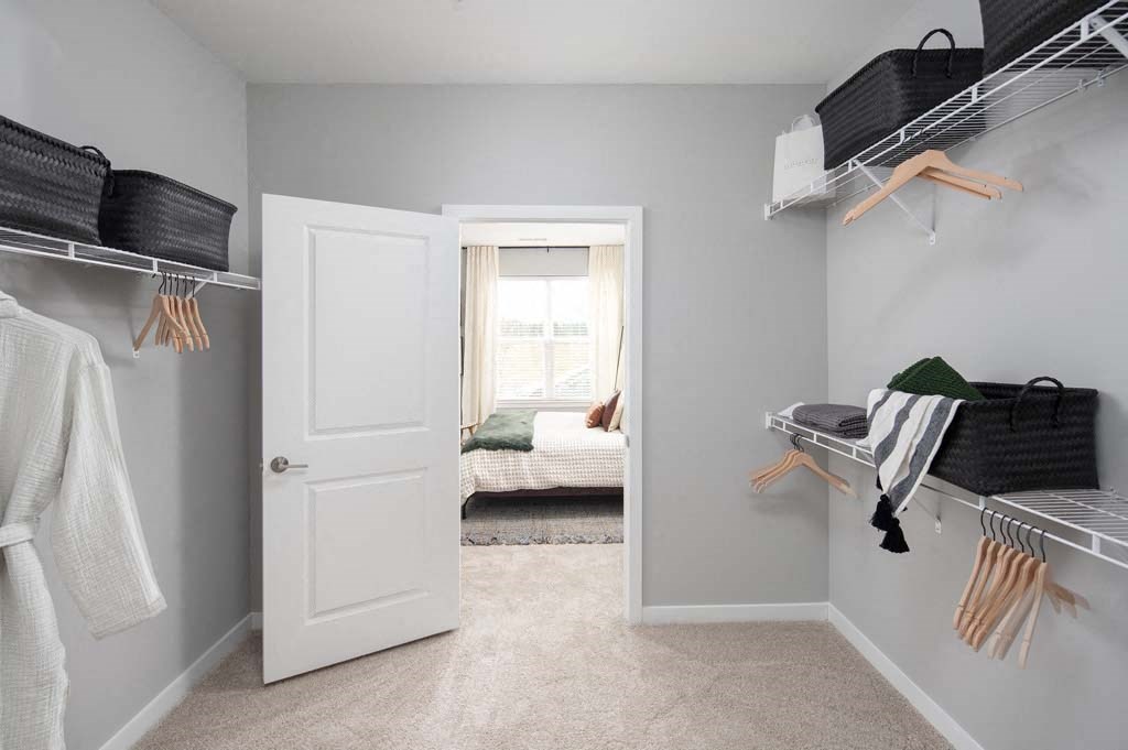 a walk in closet filled with clothes and a window