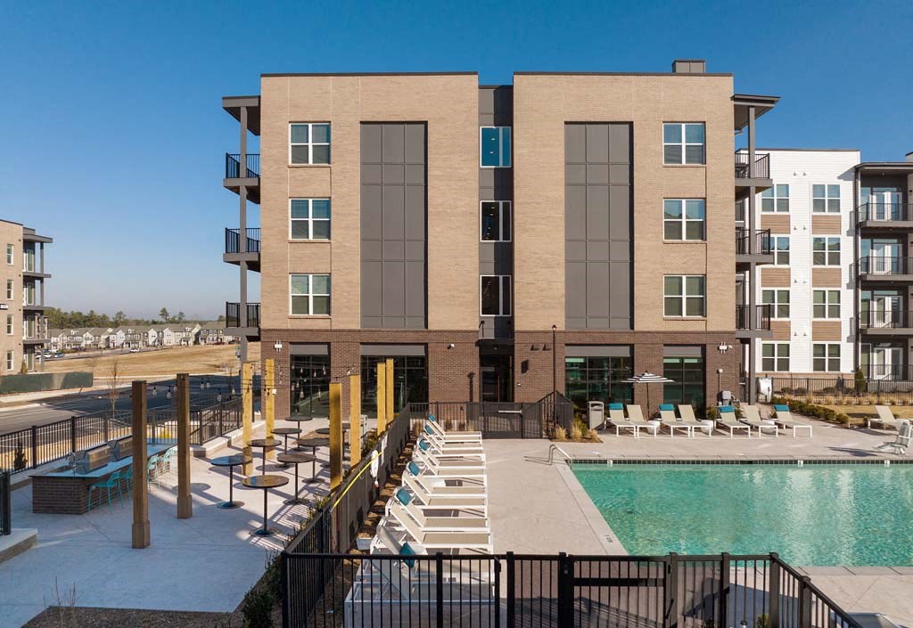 a building with a pool and chairs in front of it