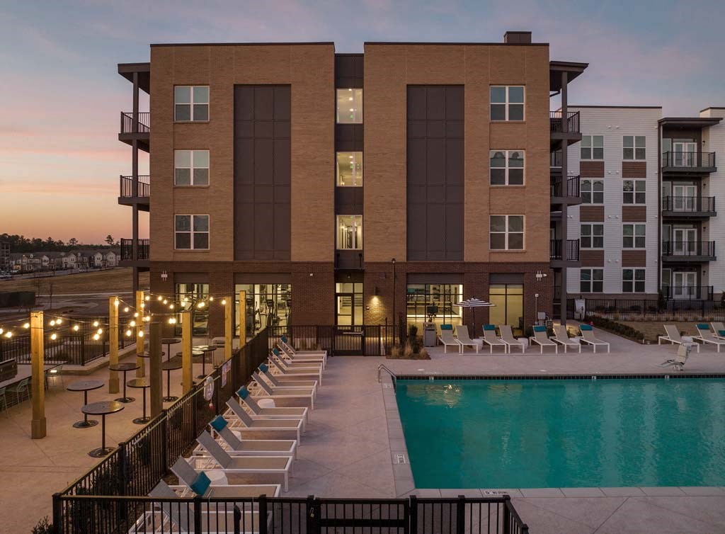 a building with a pool and chairs at dusk
