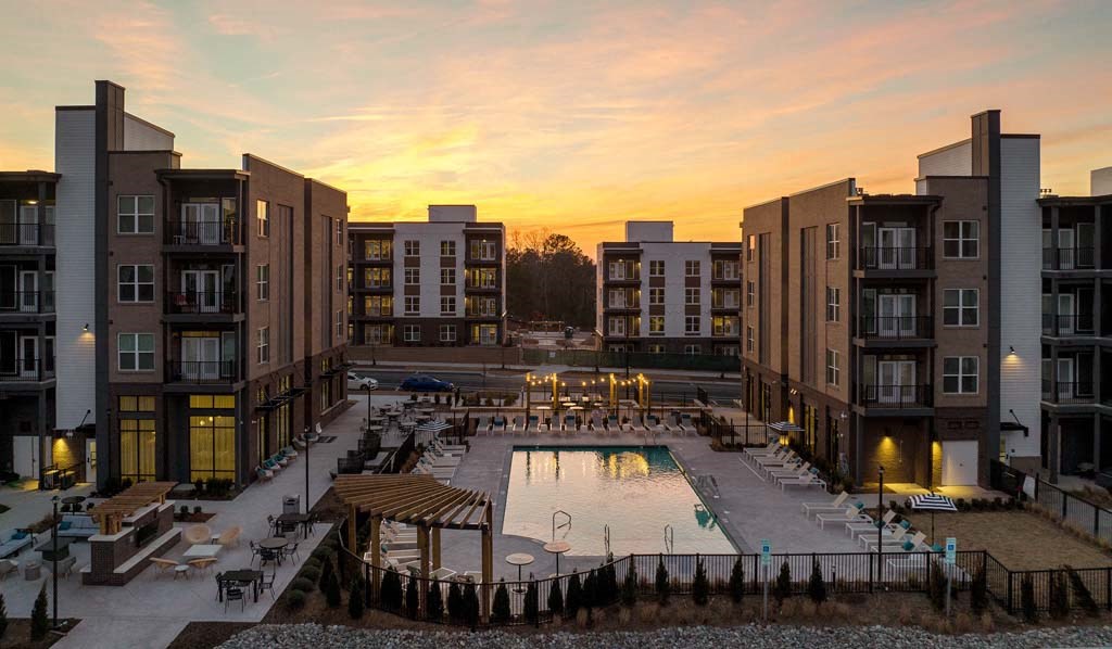 an apartment complex with a swimming pool at sunset
