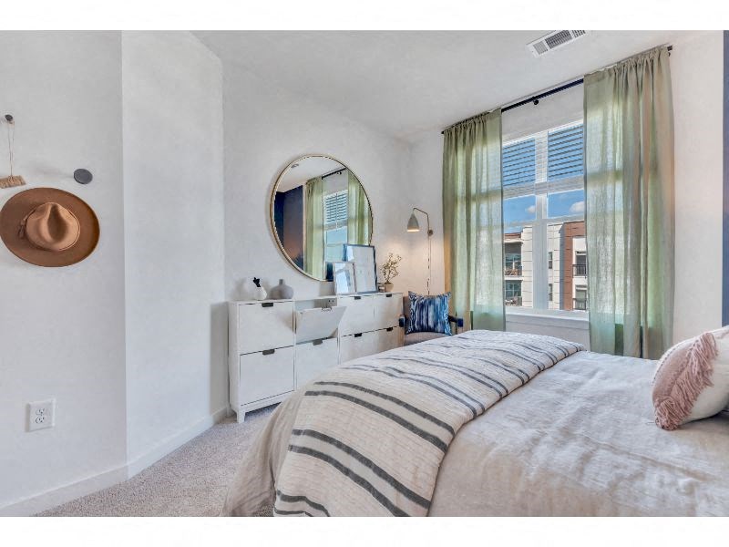 a bedroom with a bed and a mirror and a window