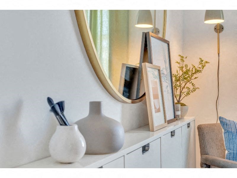 a white shelf with a mirror and a vase on it