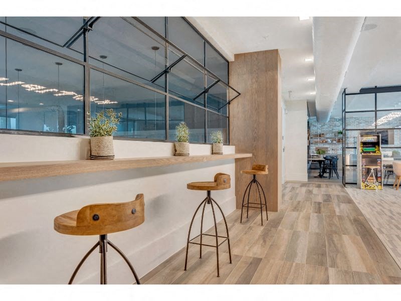 a bar with three stools in a room with large windows