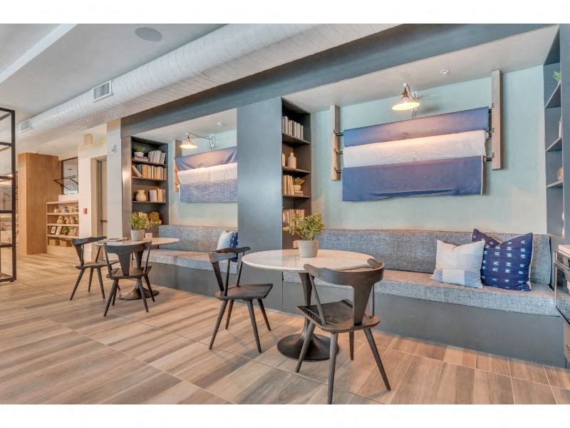 a seating area with tables and chairs and a wall with paintings