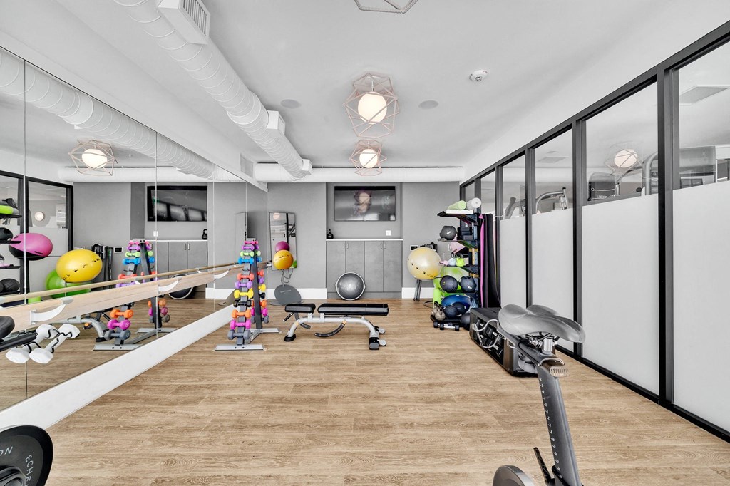 a workout room with a wood floor and mirrored walls and exercise equipment