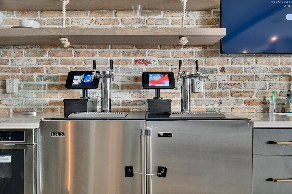 two refrigerators in a kitchen with a brick wall