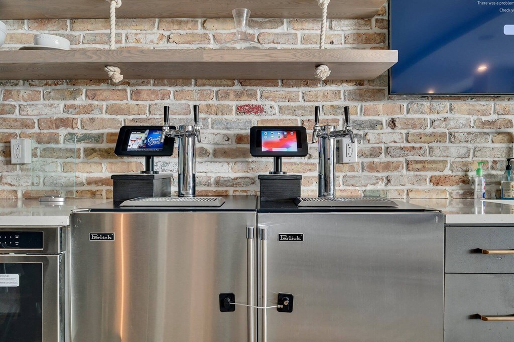 two refrigerators in a kitchen with a brick wall