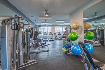 a gym with weights and cardio equipment in a building with windows