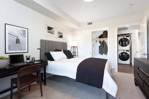 a bedroom with a bed and a washer and dryer  and a closet