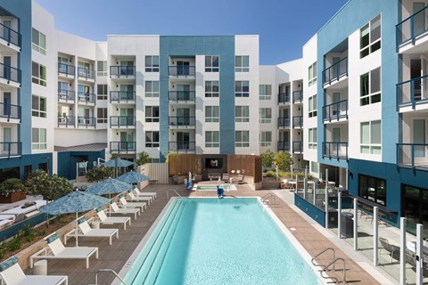 a swimming pool at an apartment building with a pool and lounge chairs