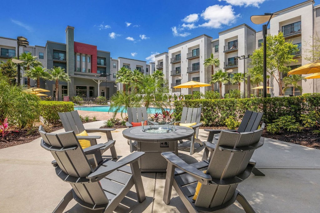 a patio with chairs and a table in front of an apartment building