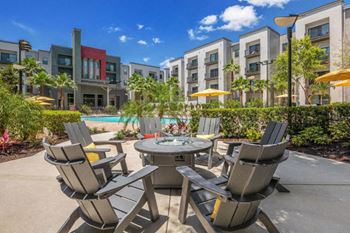 a patio with chairs and a table in front of an apartment building