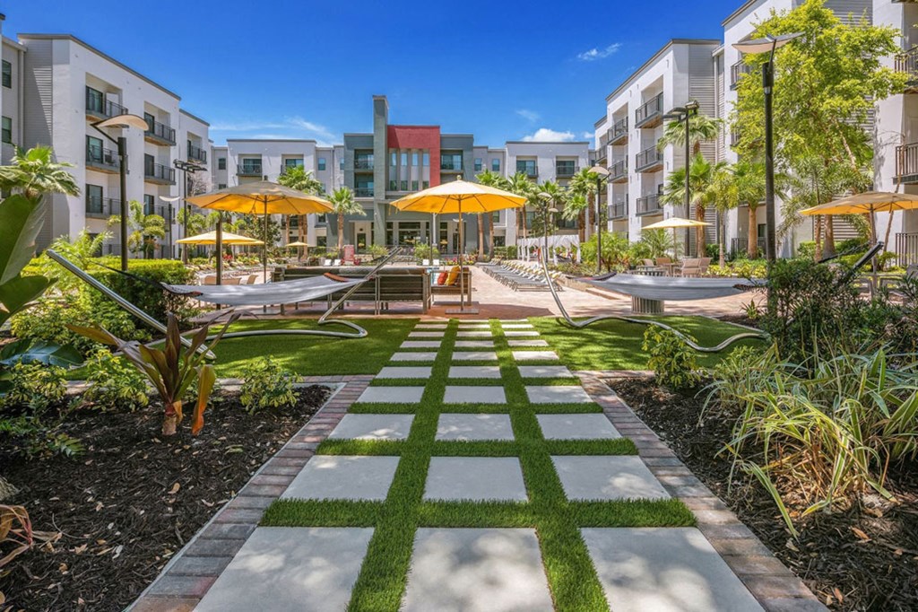 a courtyard with umbrellas and picnic tables in front of an apartment building