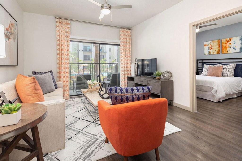 a living room and bedroom with a couch and chair and a tv