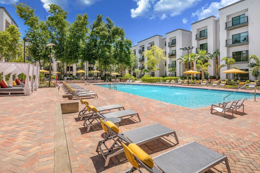 a swimming pool with lounge chairs and buildings in the background