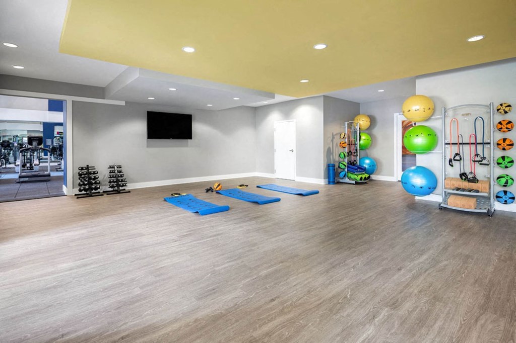 a yoga room with yoga mats and colorful balls and a television on the wall