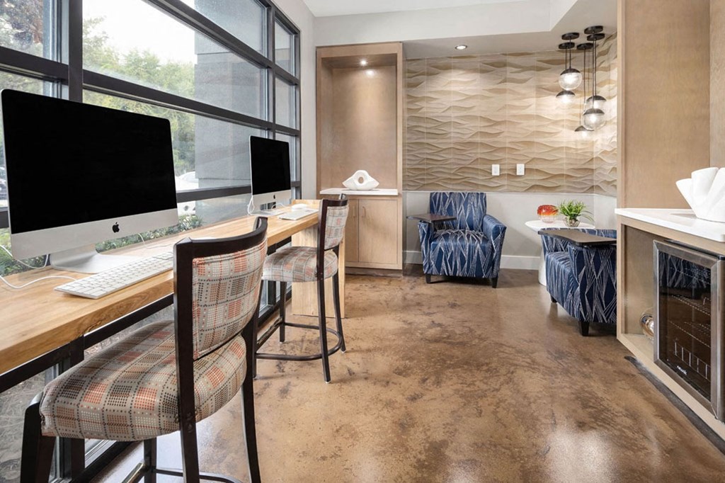 a desk with a computer and chairs in a room with a window
