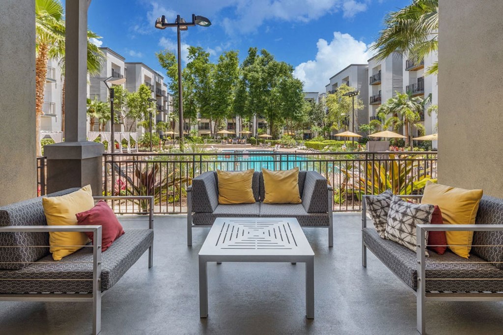 a patio with couches and a coffee table in front of a pool
