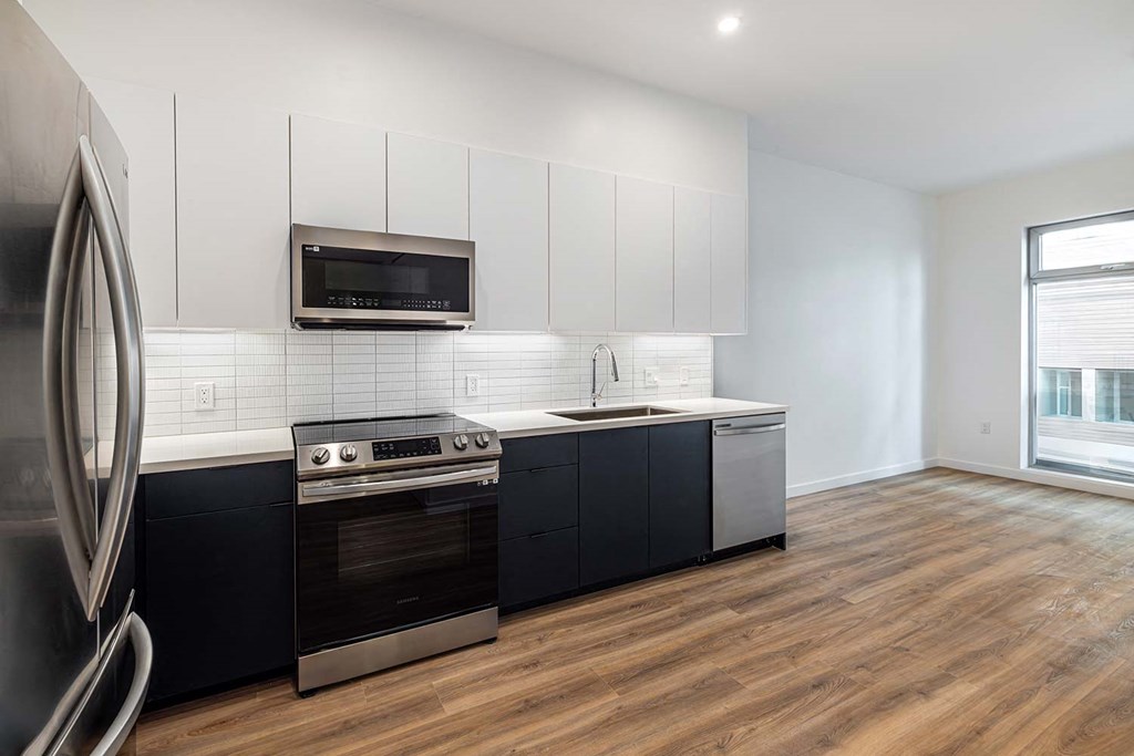 a kitchen with black and white cabinets and stainless steel appliances