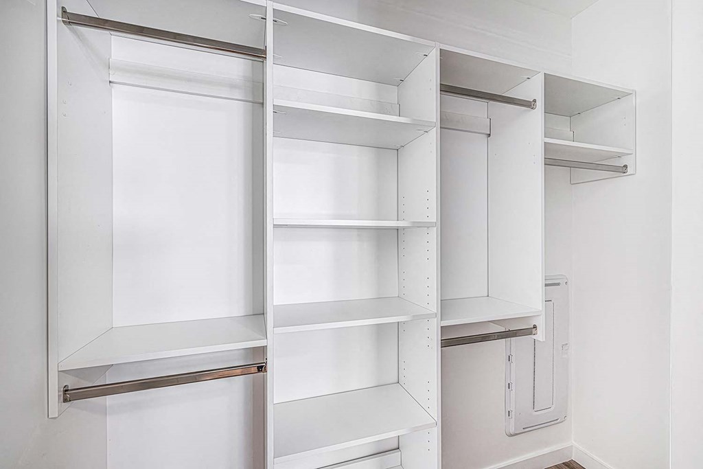 a walk in closet with white walls and shelves and