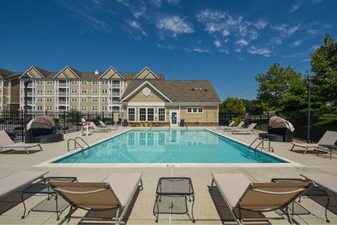 a swimming pool with chairs and a building in the background