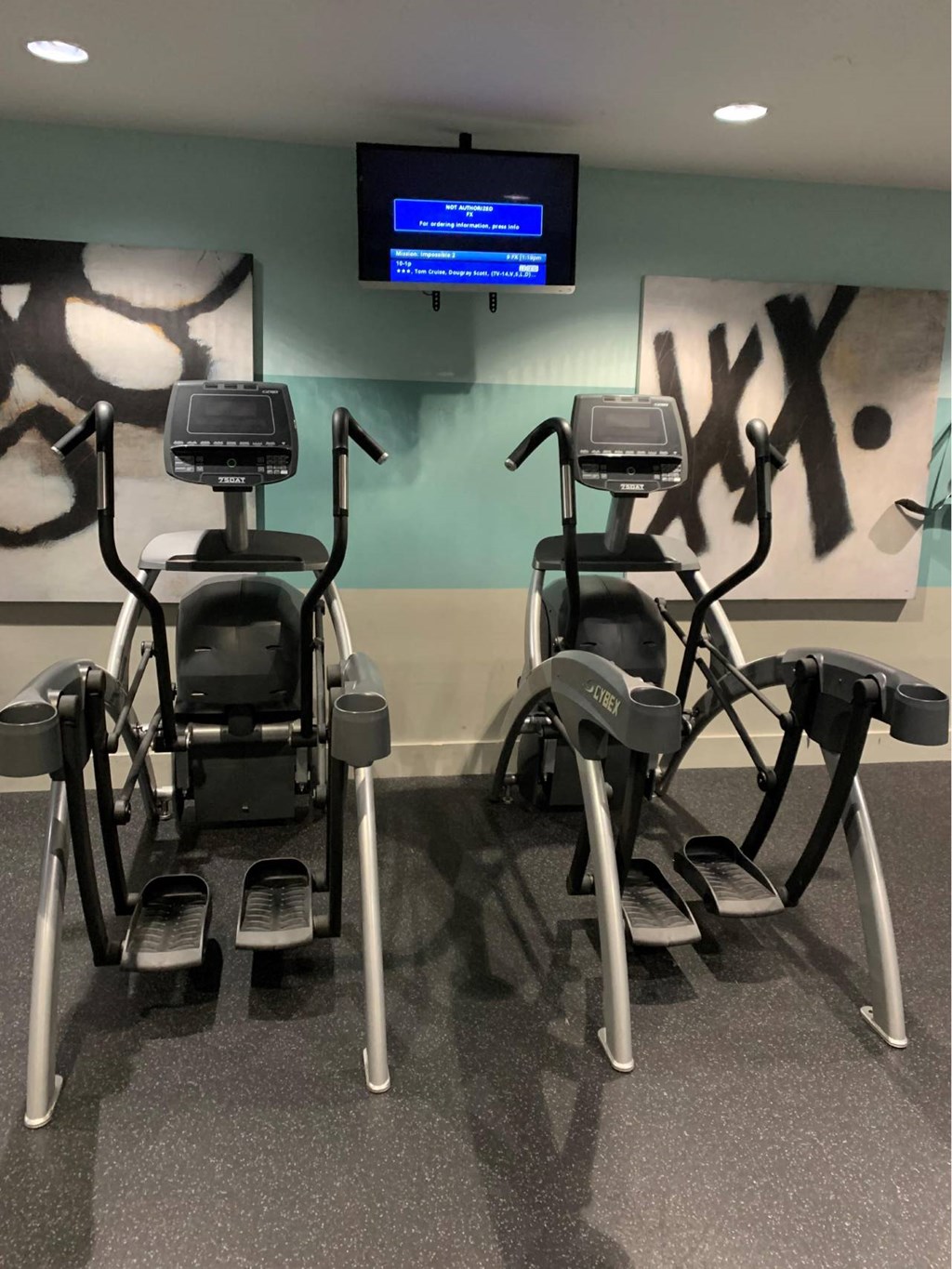 a gym with several exercise bikes and a tv