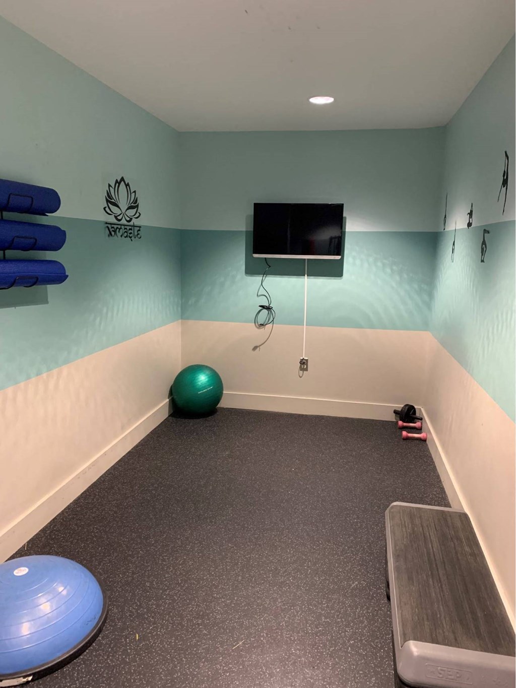 a workout room in a gym with a tv and a yoga ball
