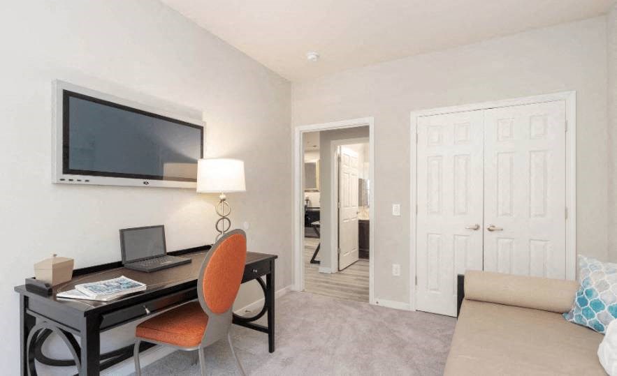 a living room with a desk and a television