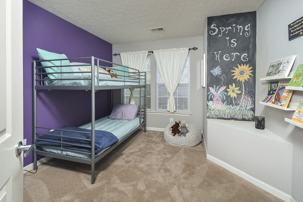 a kids bedroom with bunk beds and a chalkboard wall