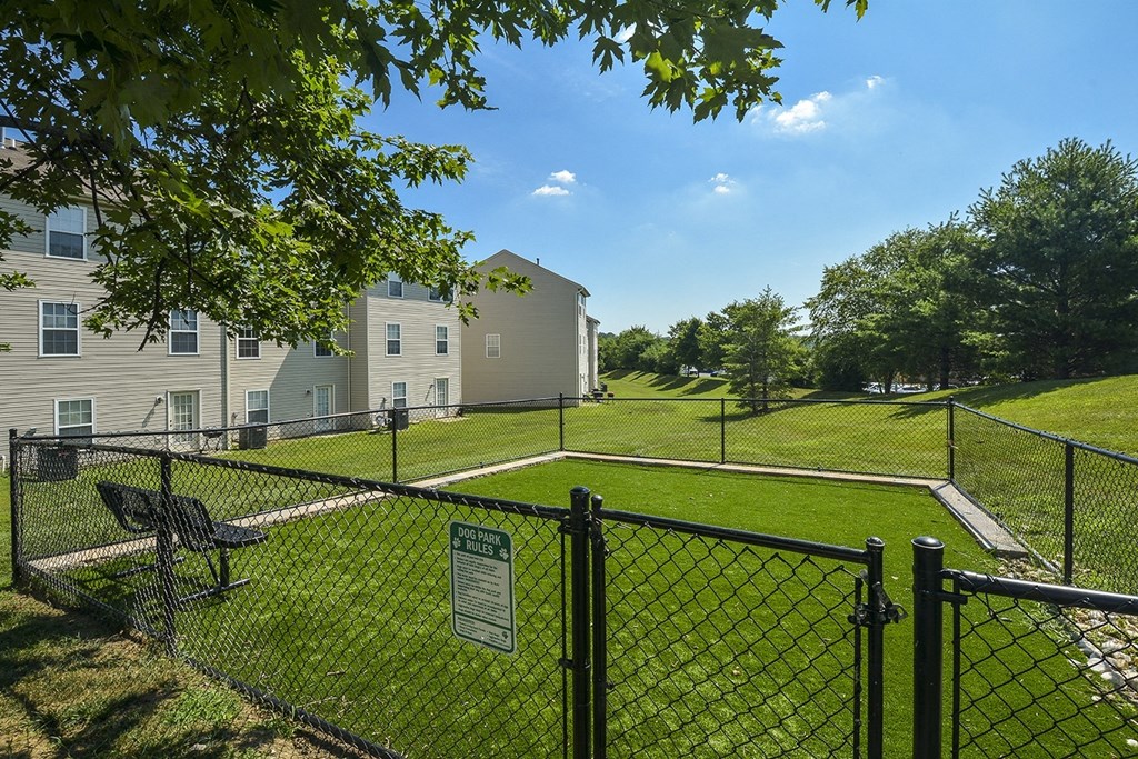 a fenced in yard with a tennis court in front of apartment buildings