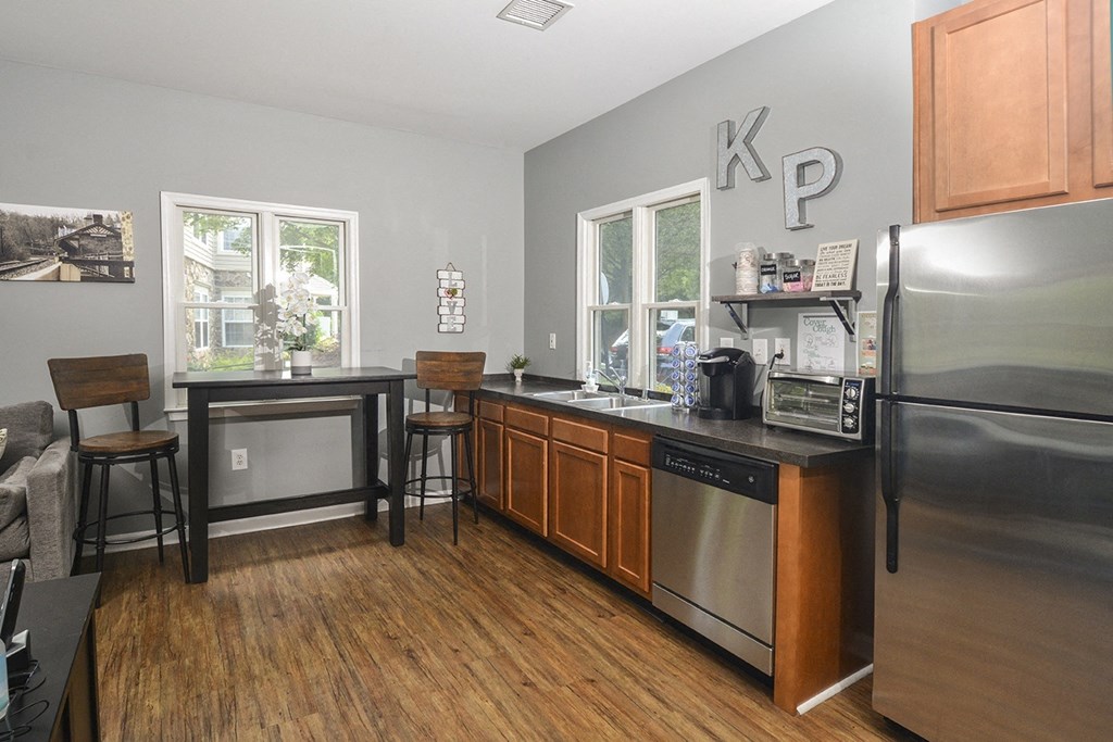 a kitchen with a stainless steel refrigerator and a counter with stools