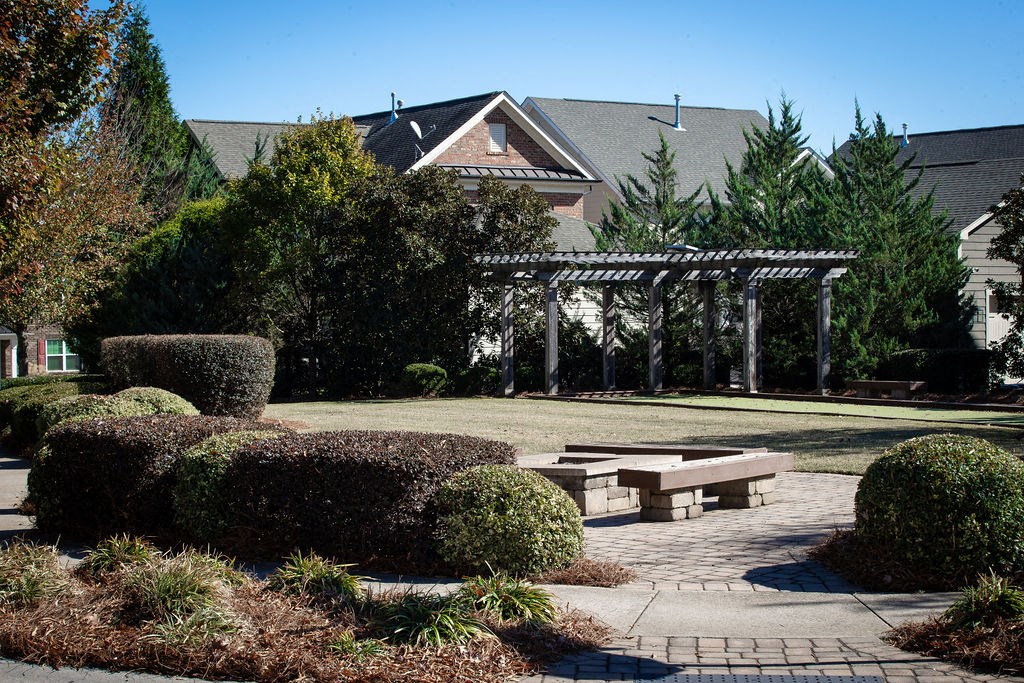 a courtyard with benches and a pergola in front of a house