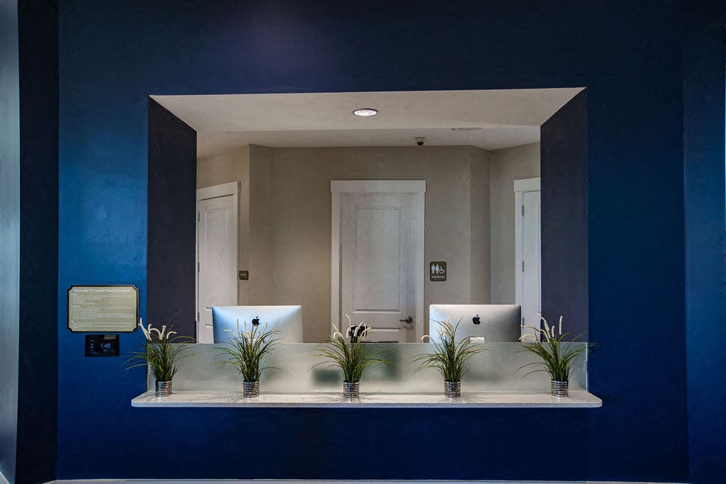 a blue wall with a mirror with a desk with two computers