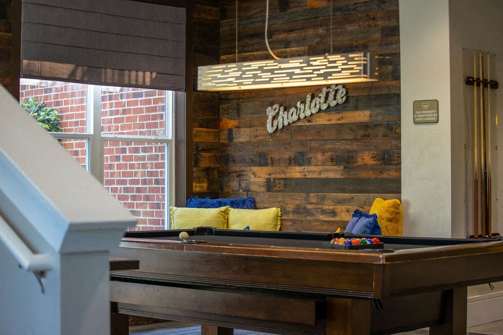 a pool table in a living room with a couch and a window