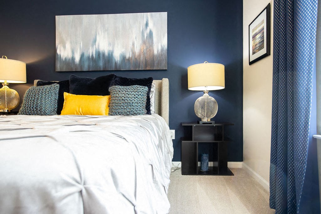 a bedroom with blue walls and a bed with yellow and blue pillows