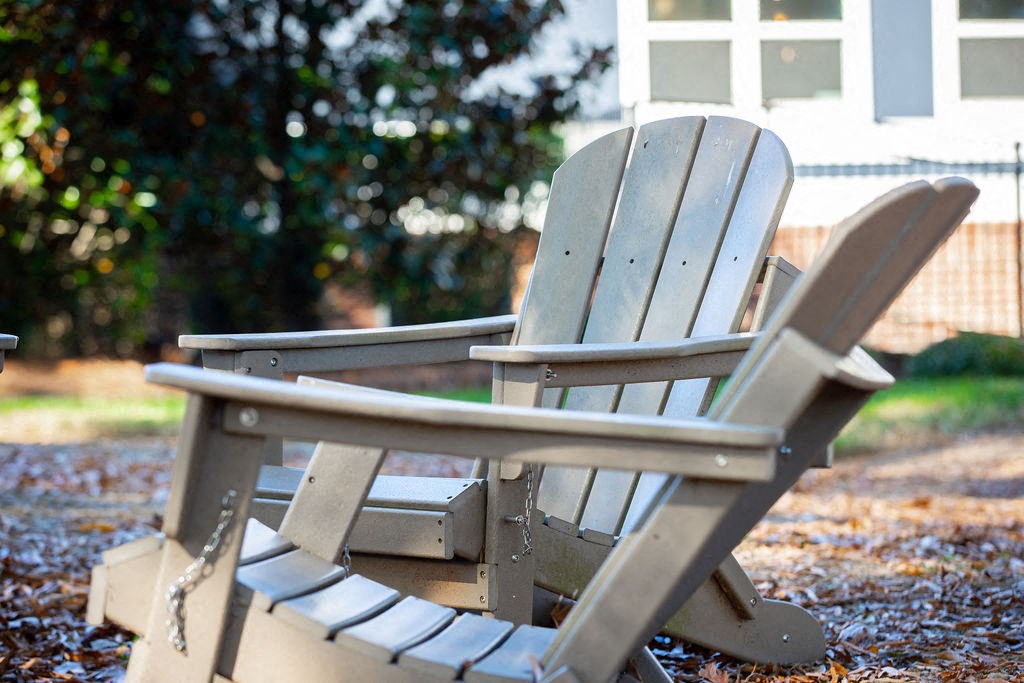 two wooden adirondack chairs in front of a house