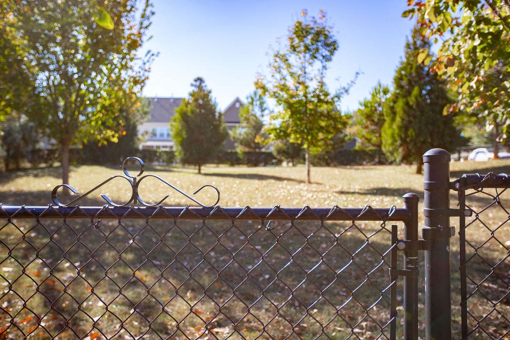 a chain link fence in front of a field with a house